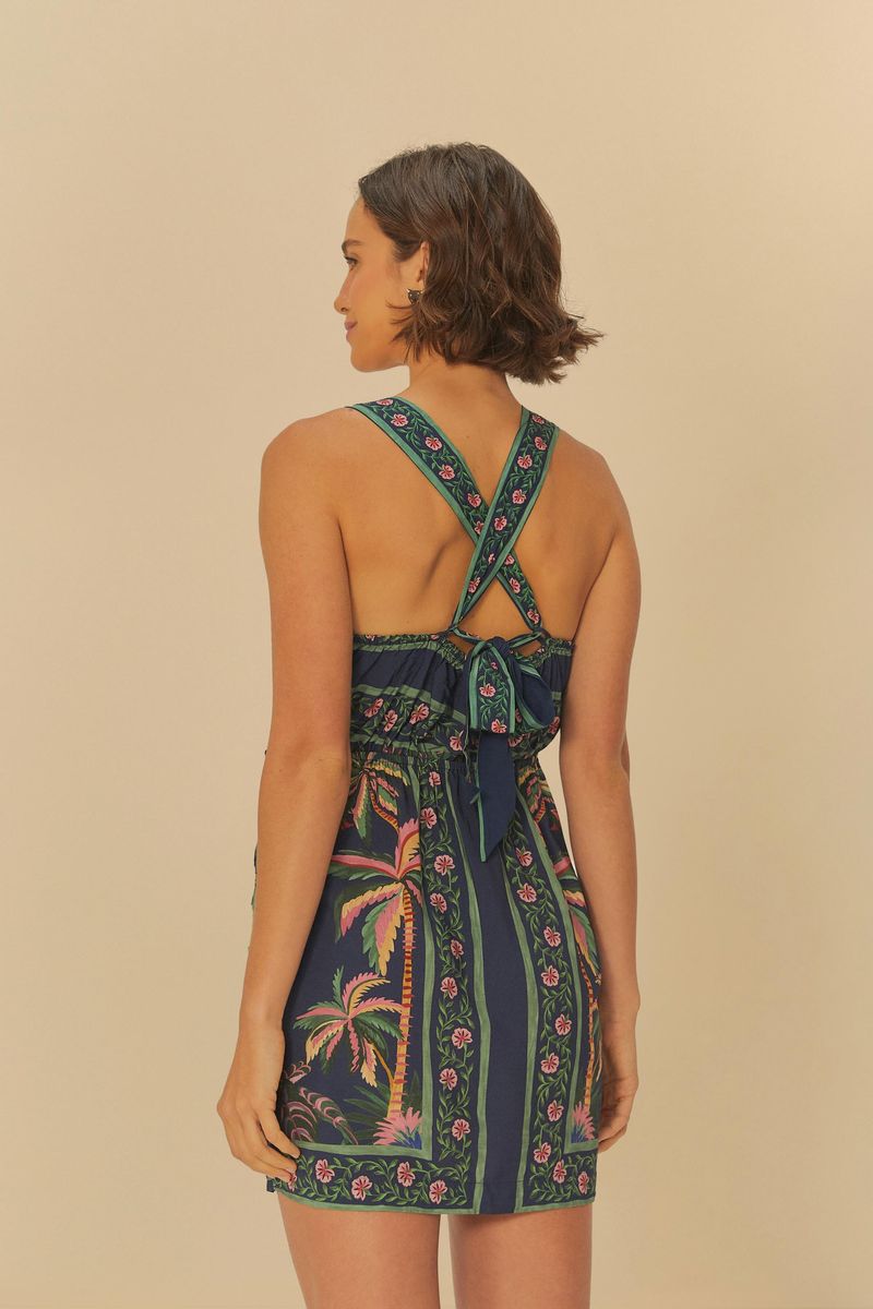 Vestido corto con estampado tropical, tirantes cruzados en la espalda y detalle de amarre, visto desde atrás.