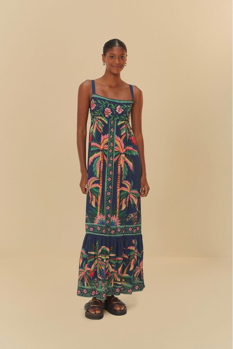 Modelo vistiendo vestido cropped con estampado tropical sobre fondo azul oscuro, vista frontal.