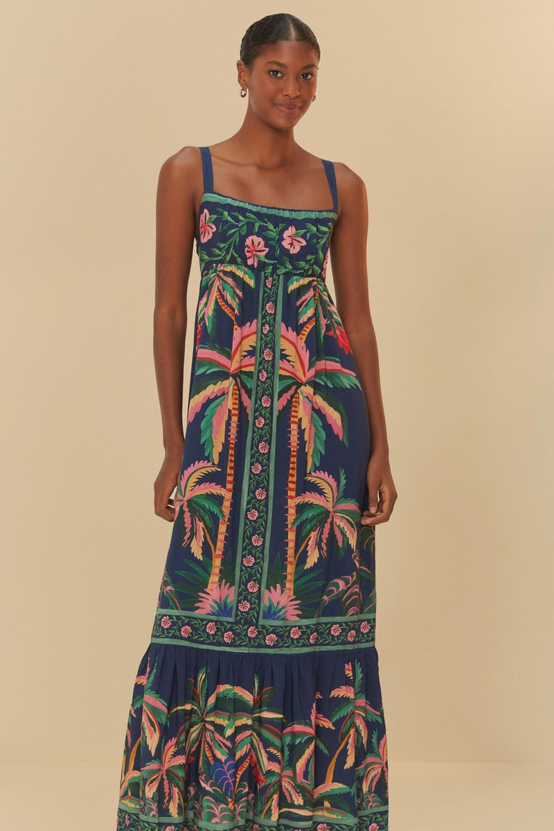 Modelo de perfil usando vestido estampado con flores y follaje, fondo azul oscuro.