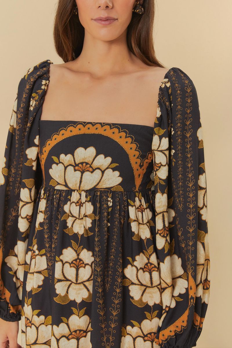 Detalle del vestido corto mostrando el escote cuadrado y el estampado floral en tonos negro, blanco y naranja.