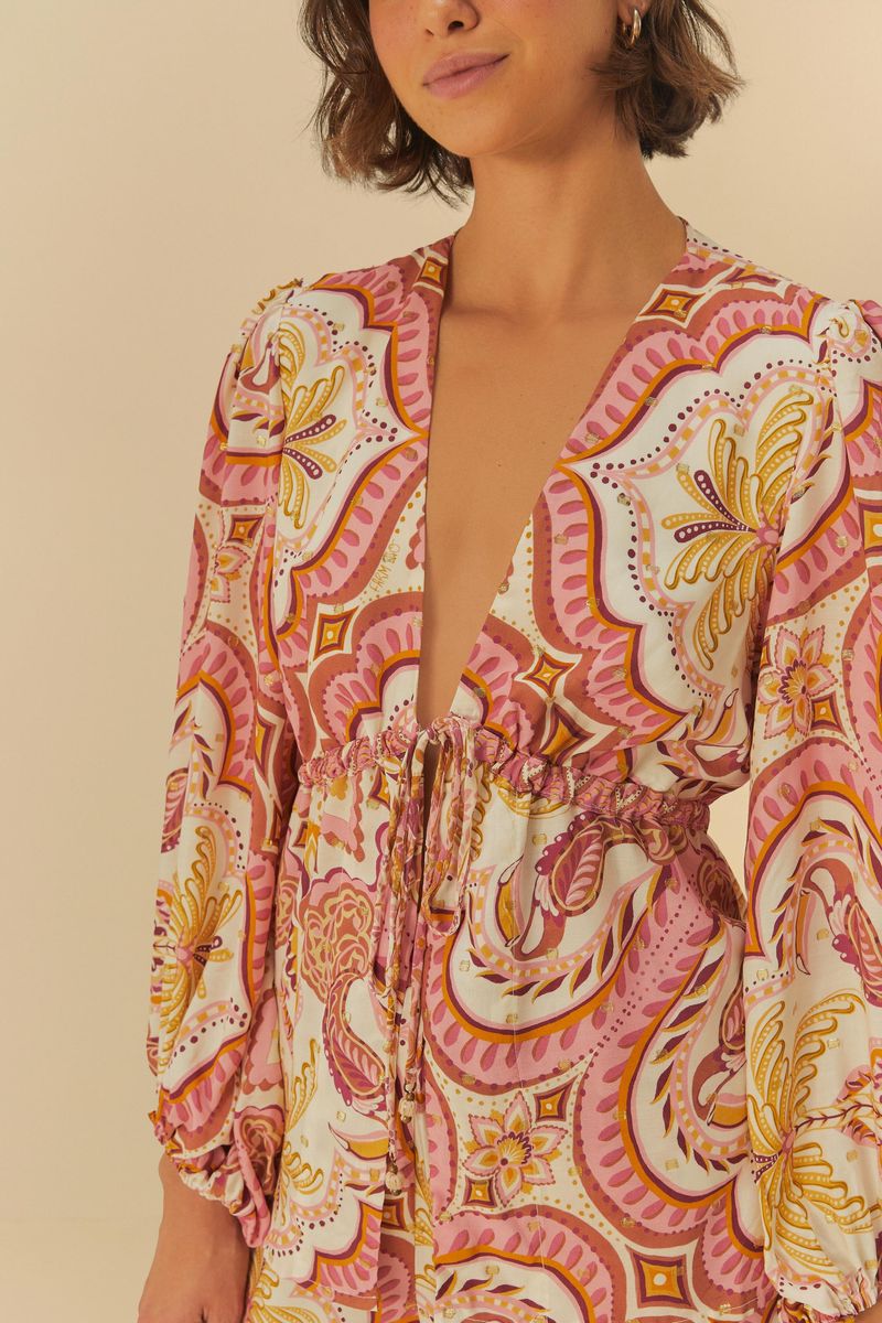 Imagen de una blusa estampada con motivo tropical, detalle del escote en V y ajuste en la cintura.