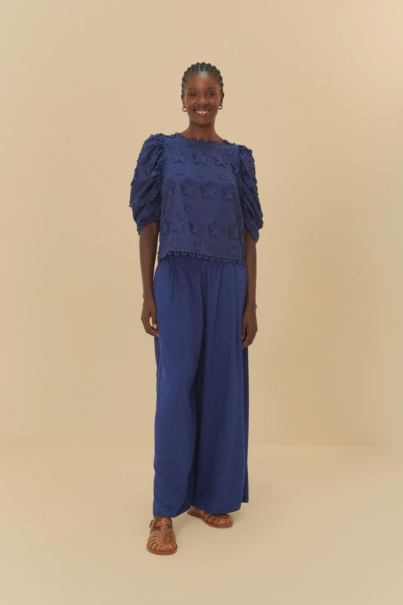 Modelo con pantalón de lino azul oscuro con cintura elástica y blusa decorada