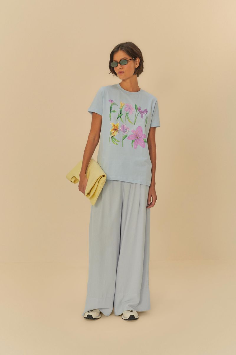 Modelo usando pantalón azul claro de lino con camiseta estampada, sosteniendo una bolsa amarilla.