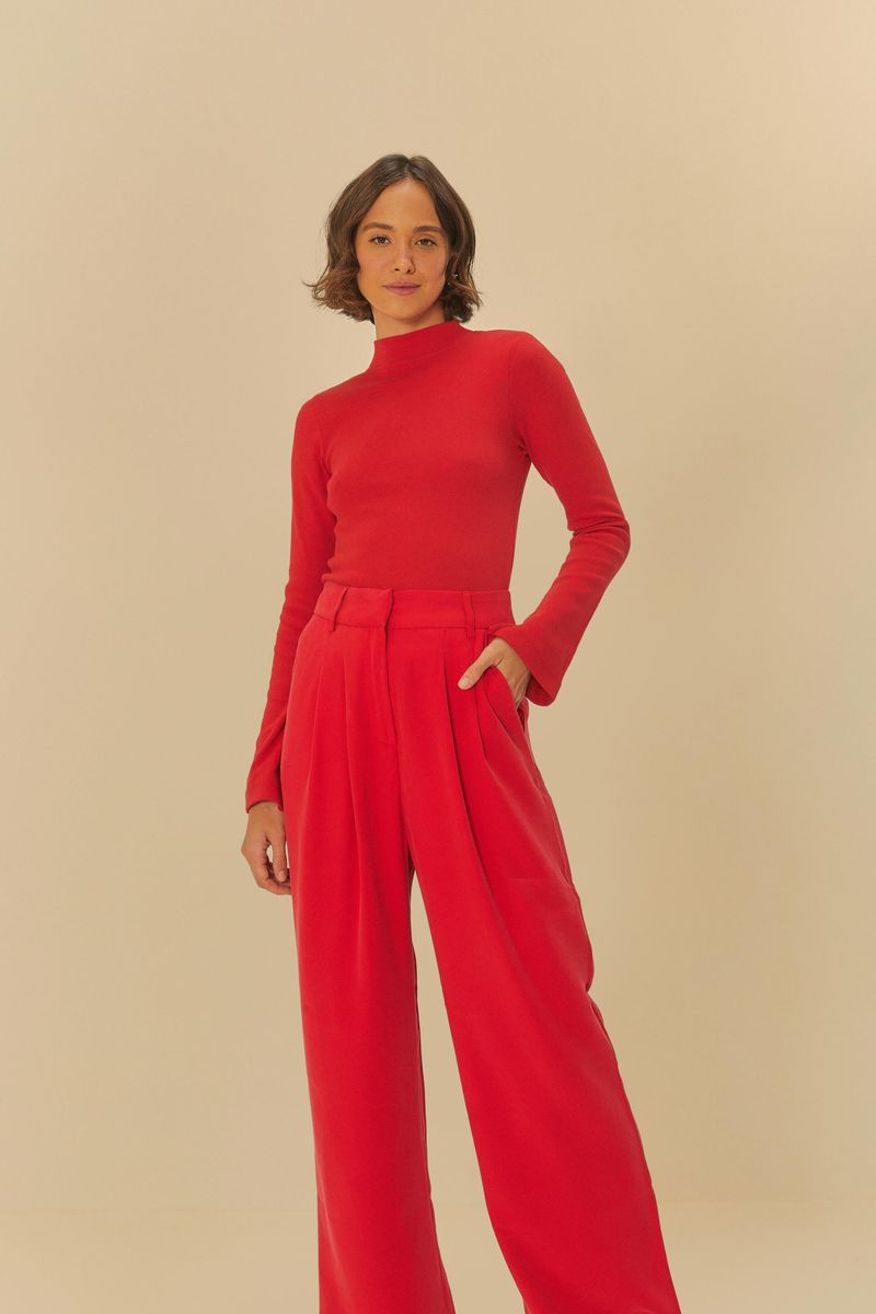 Modelo llevando pantalón recto de sastrería rojo con blusa de manga larga roja, vista lateral.