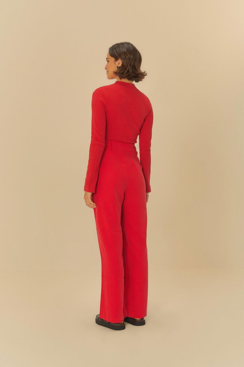 Modelo llevando pantalón recto de sastrería rojo con blusa de manga larga roja, vista trasera.