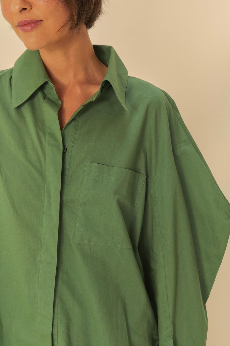 Detalle del cuello puntiagudo y cierre con botones de la camisa básica de algodón verde.