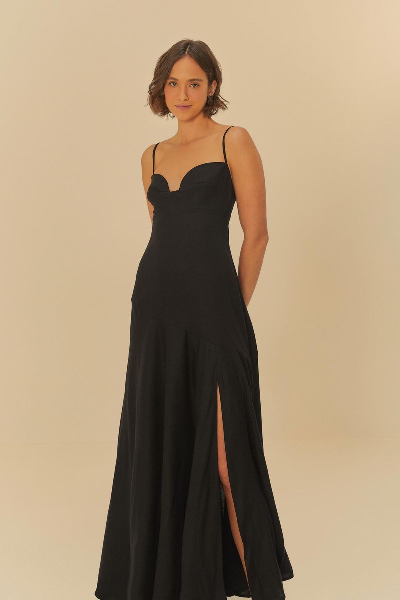 Vestido negro con tirantes delgados y abertura frontal, visto desde el lado.