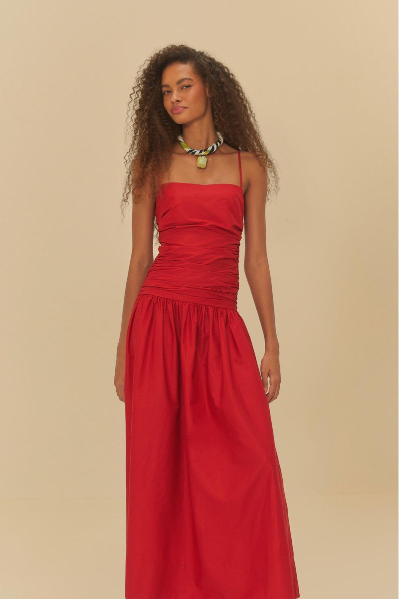 Imagen de un vestido rojo con fruncidos en la parte superior y tirantes delgados, visto de lado.