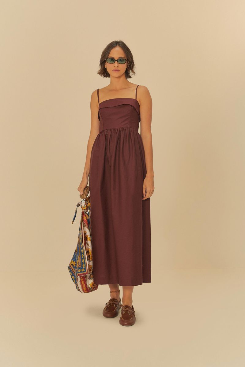 Vestido-largo-con-finos-tirantes-en-tono-vino-exhibido-en-modelo-de-frente-sosteniendo-un-bolso-colorido.