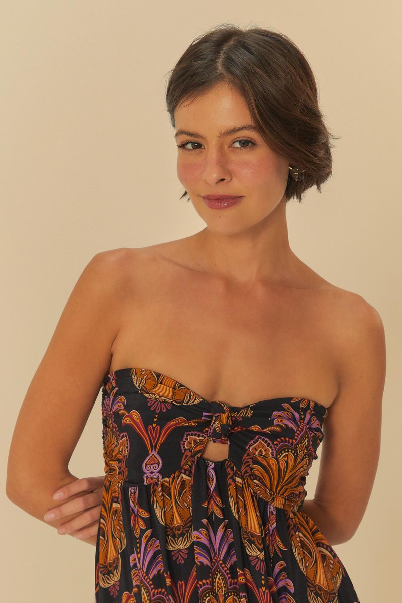 Imagen mostrando un vestido largo estampado con patrón boho, con detalles en naranja y morado sobre fondo negro, visto de espaldas.