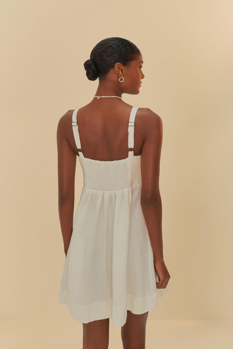 Vista trasera del vestido corto blanco con tirantes anchos y detalle de lazado en la cintura.