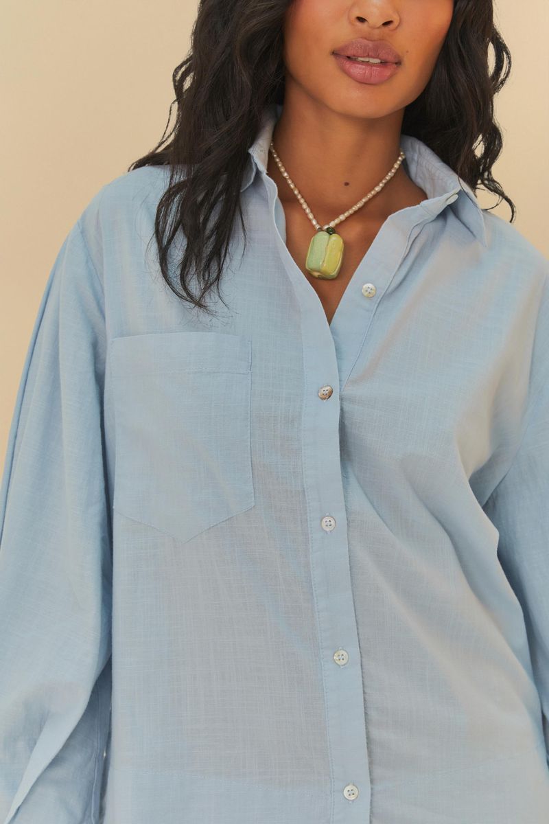 Detalle del cuello y cierre con botones de la camisa azul clara.