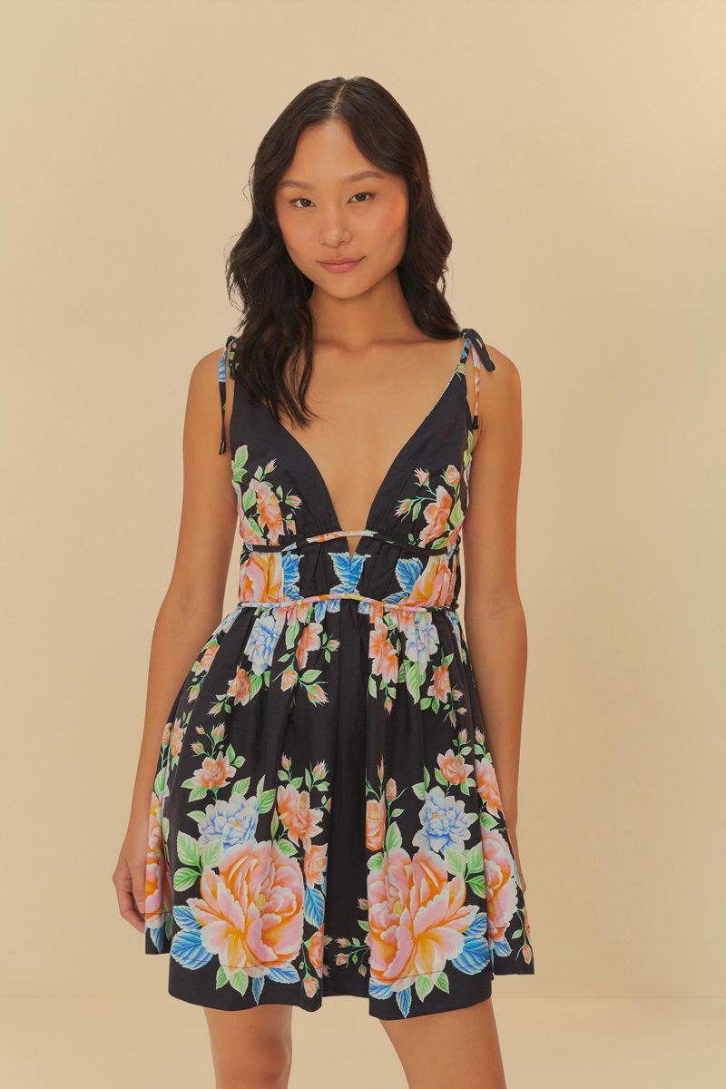 Vestido corto con estampado floral sobre fondo negro, escote profundo en V y tirantes ajustables.