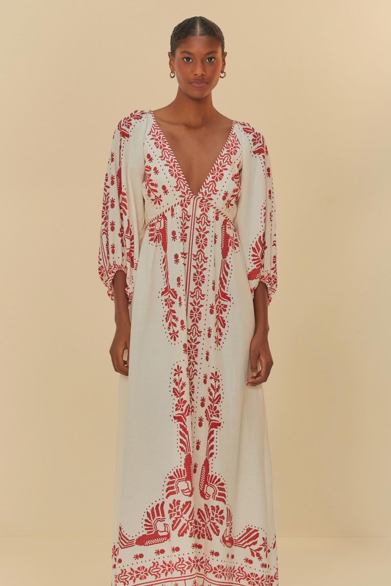 Acercamiento del vestido mostrando el bordado tropical en rojo sobre fondo blanco.