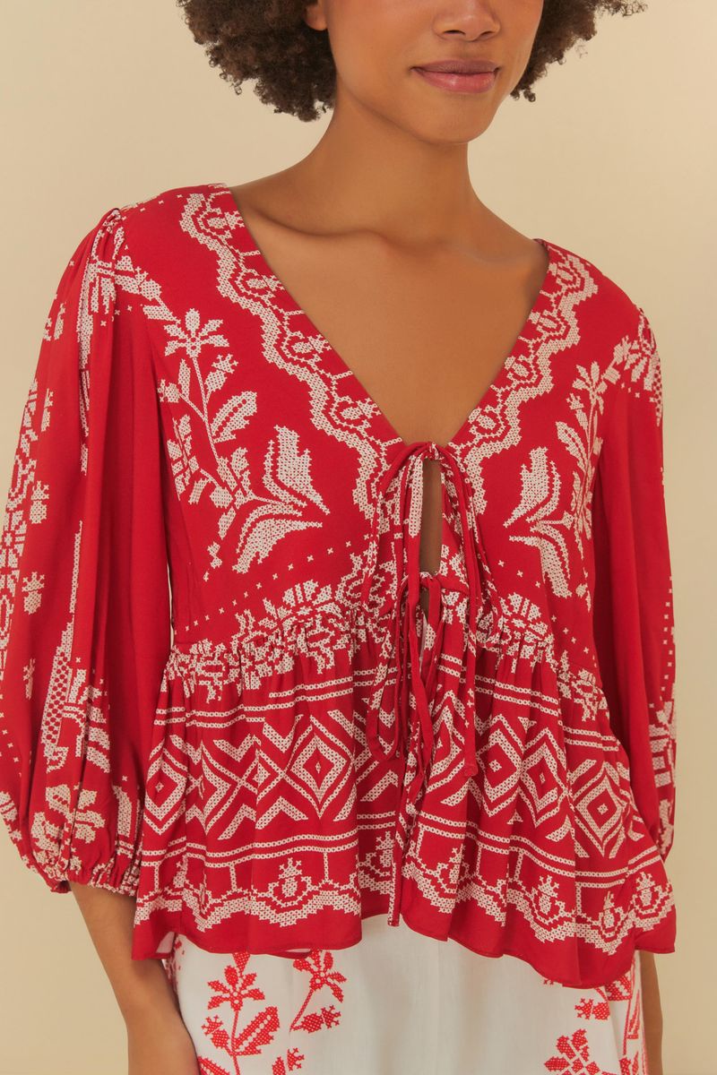 Detalle del escote en V y amarração de la bata roja con bordado tropical.