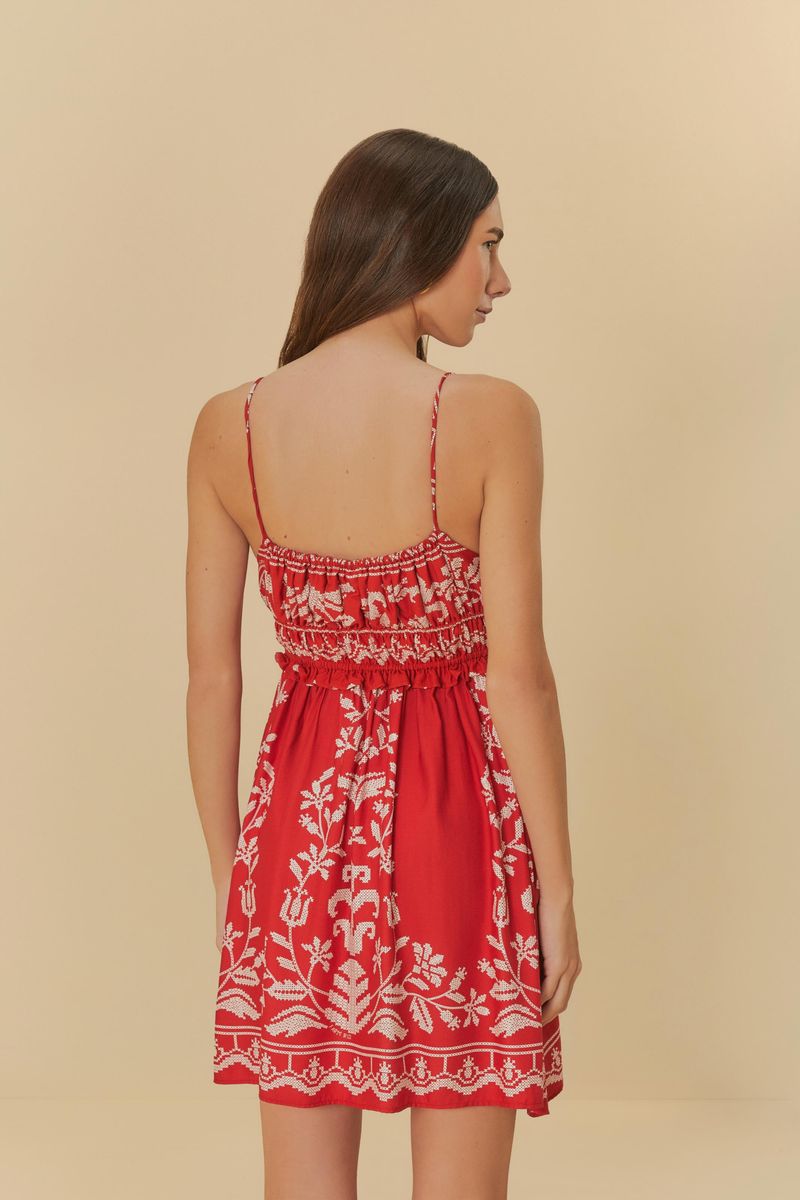Vista posterior del vestido corto rojo con bordado tropical blanco y tirantes delgados.
