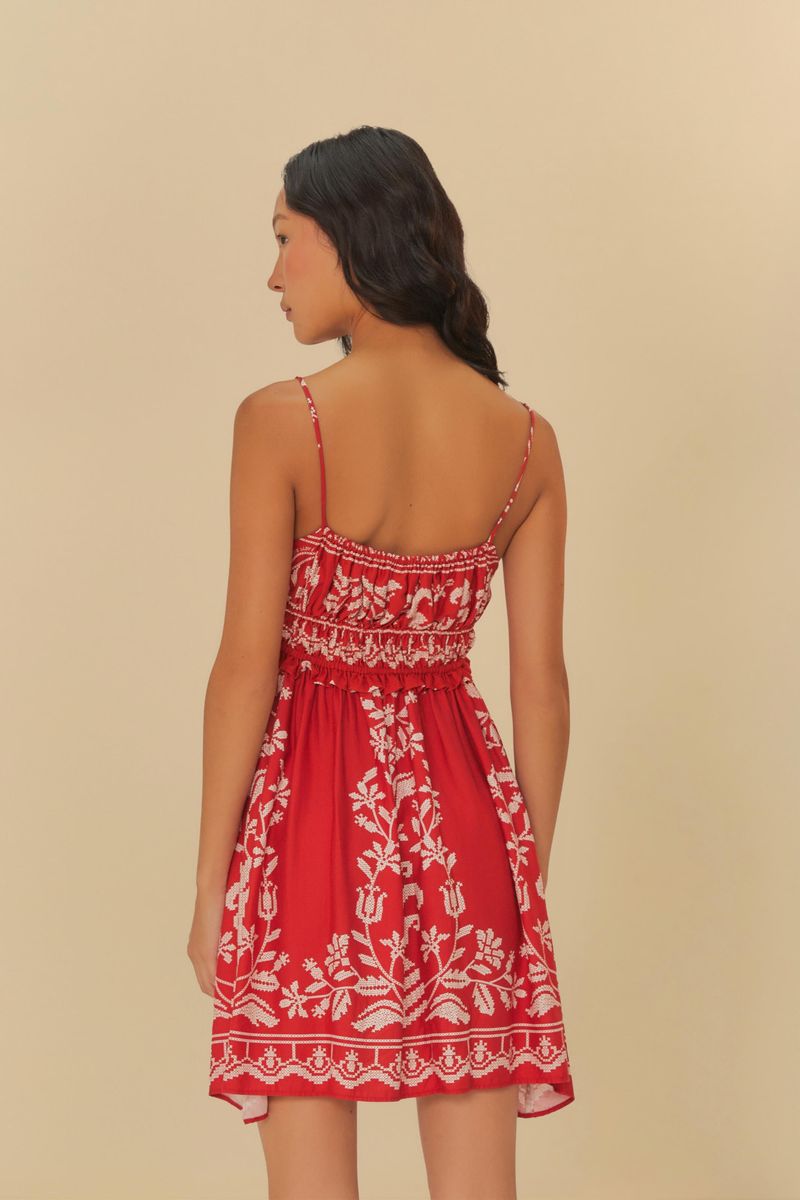 Vista lateral del vestido corto rojo con bordado tropical blanco y tirantes delgados.