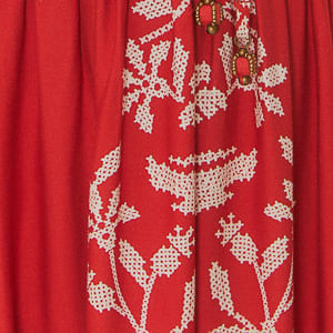 Detalle-del-dobladillo-del-vestido-mostrando-el-bordado-tropical-blanco.
