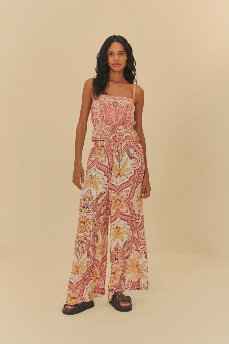 Imagen de una mujer vistiendo una regata estampada con diseño floral, combinada con pantalones anchos, vista de cuerpo entero.