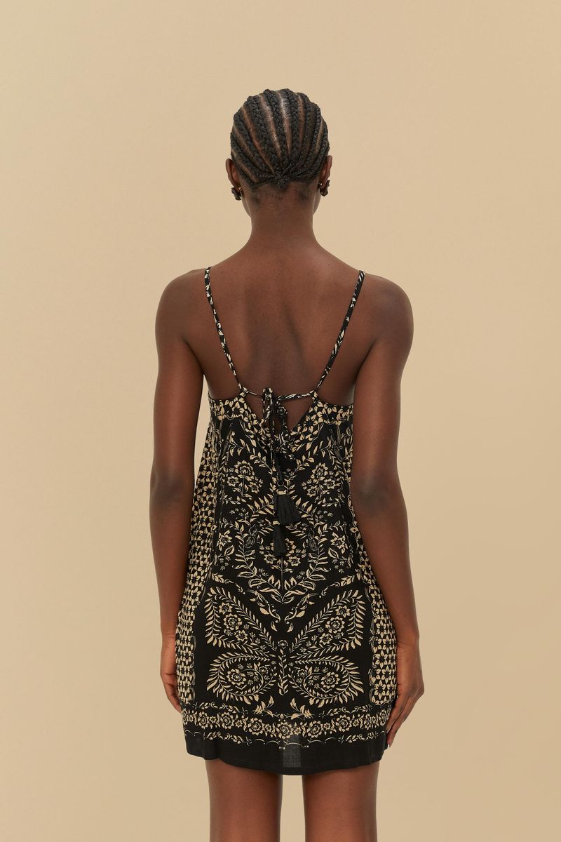 Vestido corto con estampado floral sobre fondo negro, tirantes finos y escote recto, visto desde atrás.