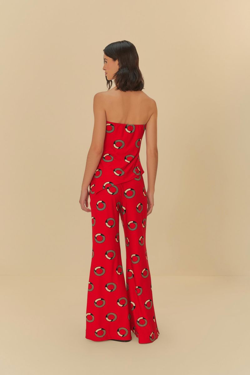 Detalle de la parte inferior del pantalón flare rojo con estampado de círculos, mostrando el ajuste y el calzado