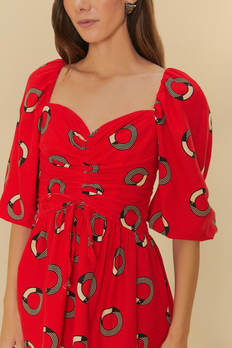 Detalle del vestido corto rojo con estampado de círculos, mostrando el escote corazón y mangas abullonadas.