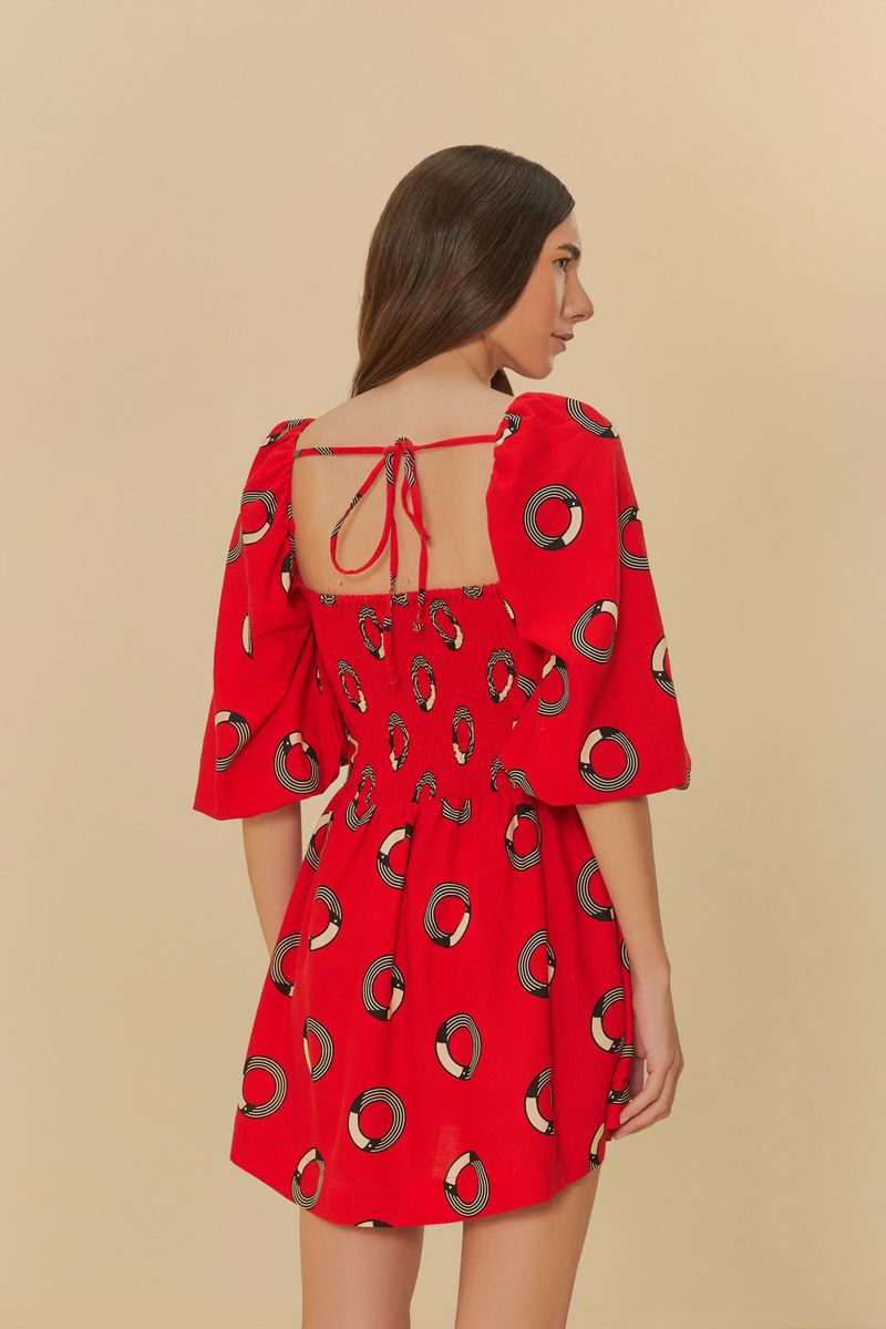 Vista trasera del vestido corto rojo con estampado de círculos, con amarre en la espalda y mangas abullonadas.