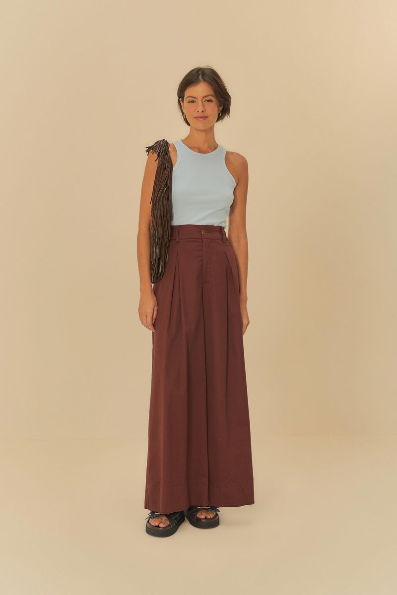 Imagen de una mujer vistiendo una regata azul claro, combinada con pantalones marrones, vista de cuerpo entero.
