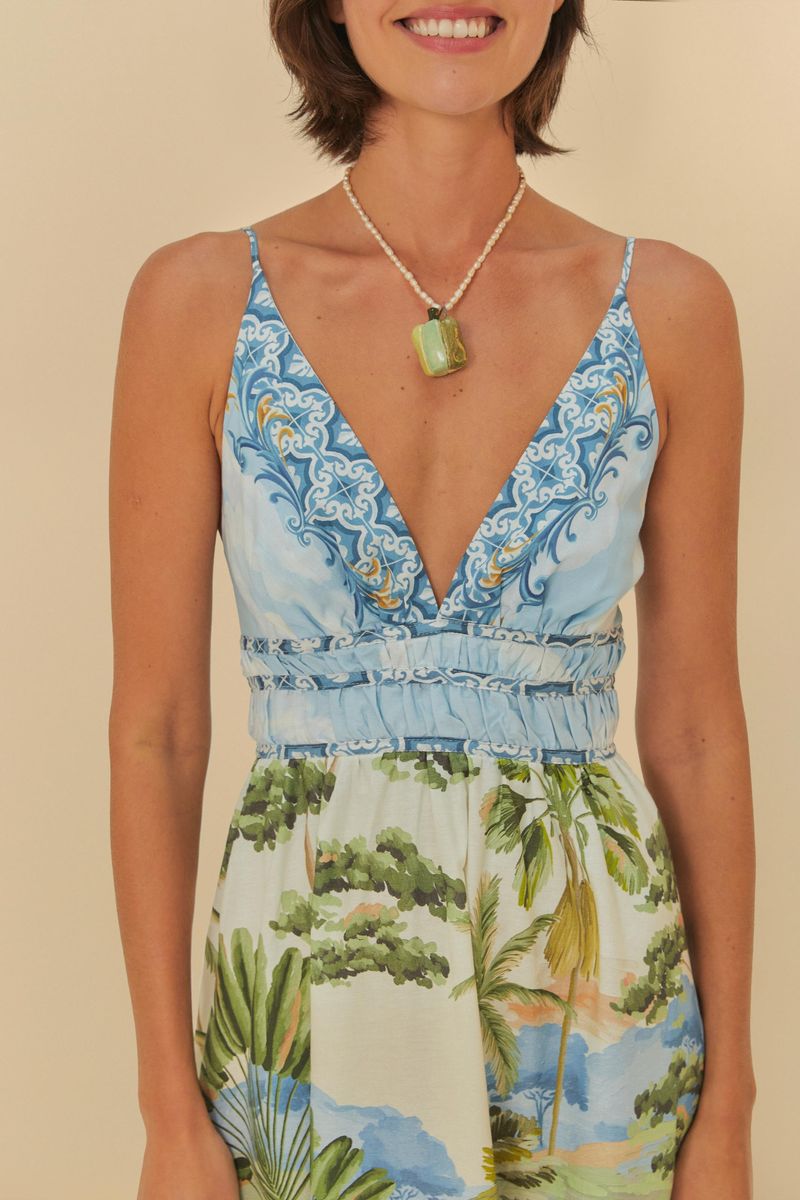 Detalle del escote en V del vestido con patrón paisaje natural y tiras delgadas.