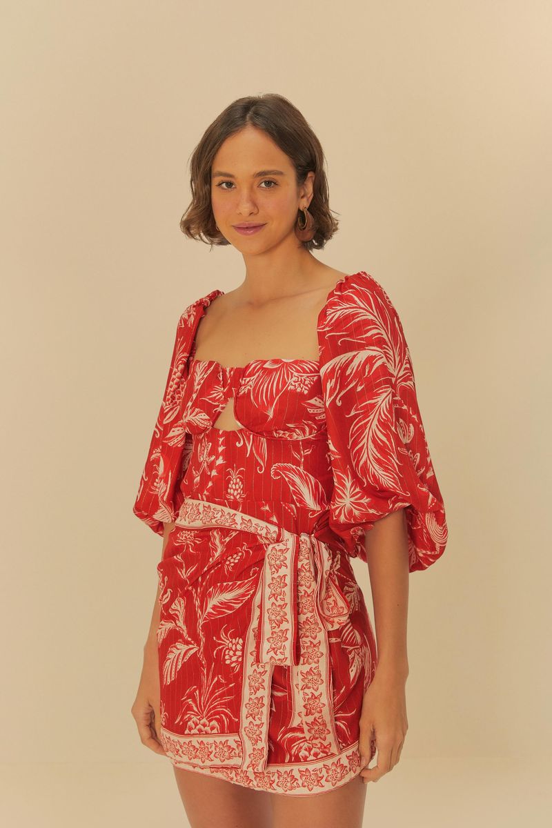 Vestido rojo corto con estampado botánico blanco, mangas abullonadas y escote cuadrado, visto de frente.