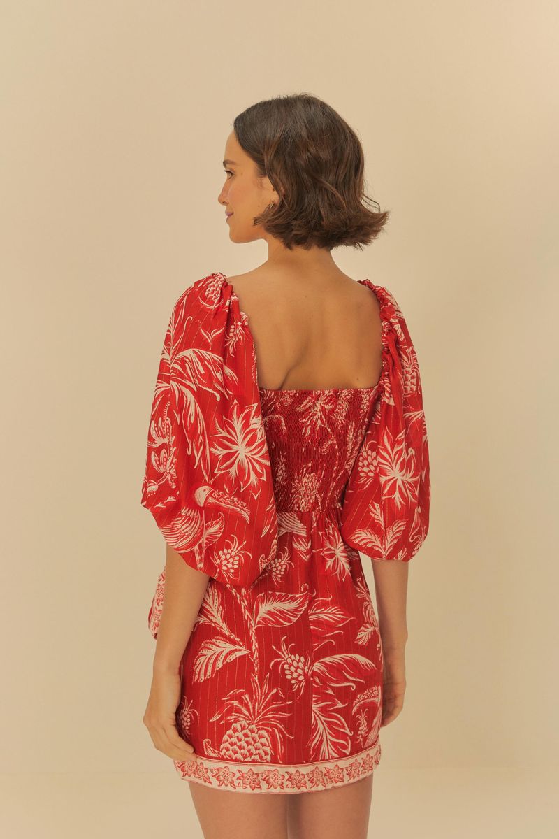 Vista trasera del vestido rojo corto con estampado botánico blanco, destacando el escote cuadrado y las mangas abullonadas.