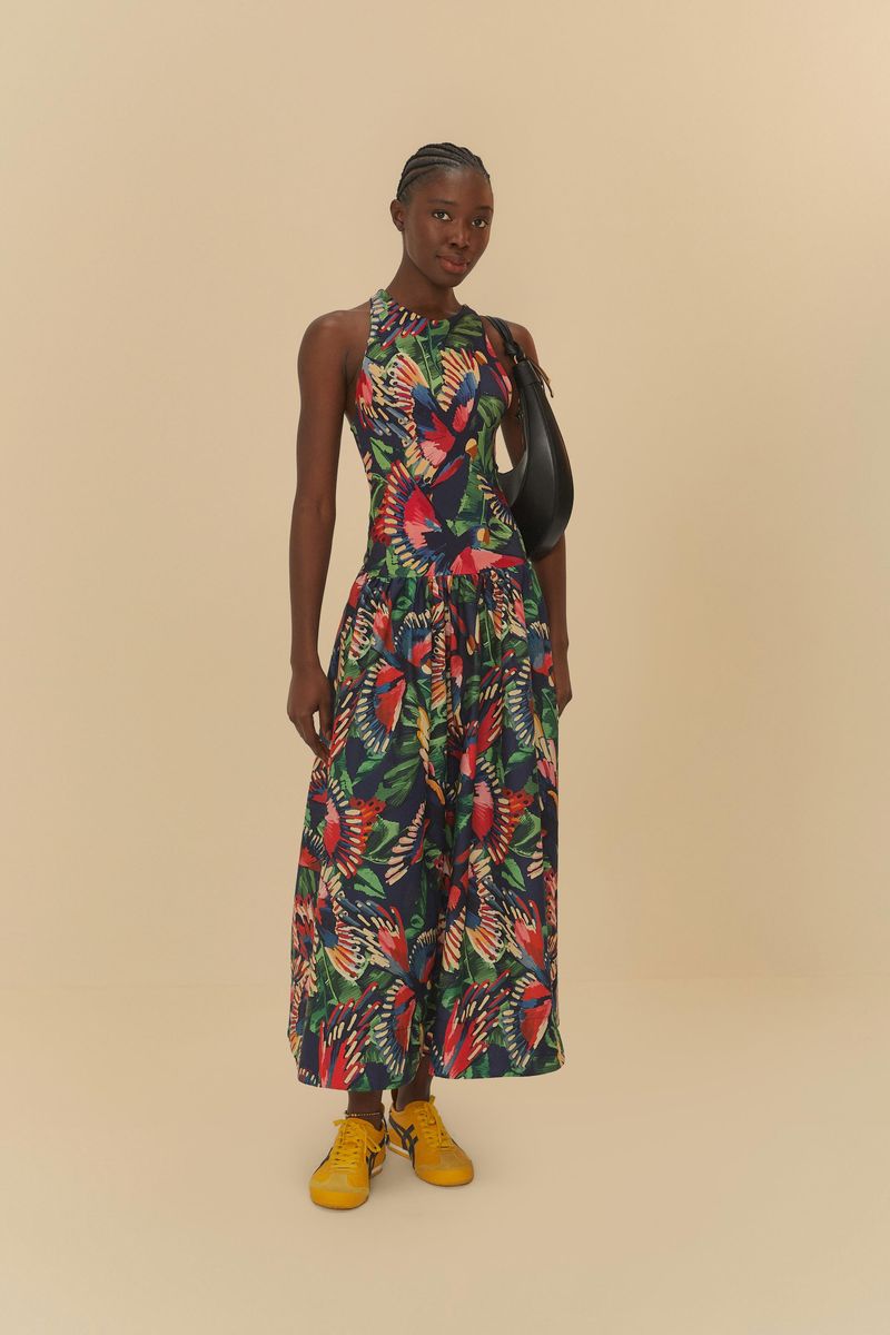 Modelo-que-viste-un-vestido-midi-estampado-con-diseño-de-pajaros-y-hojas-acompañado-de-un-bolso-negro-y-sandalias-amarillas.