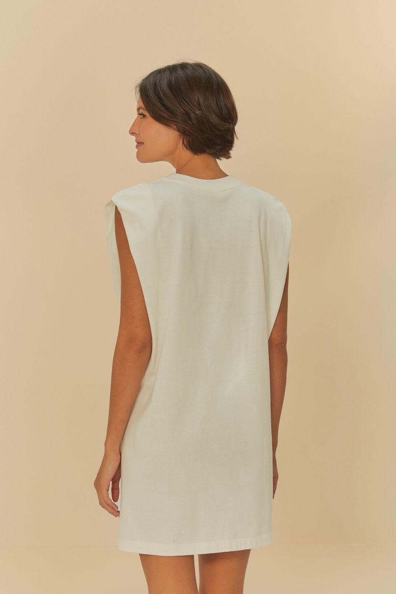 Modelo usando un vestido corto blanco con estampado, vista trasera mostrando el diseño simple.