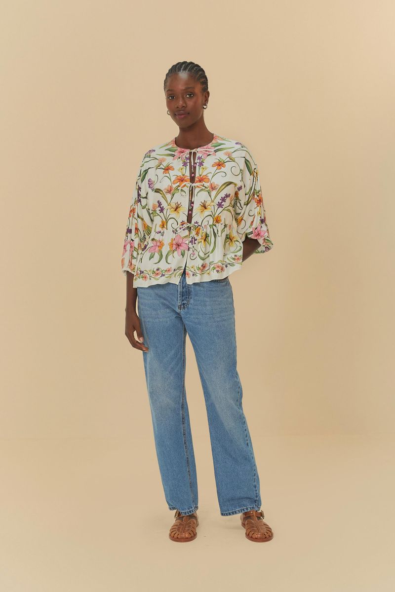 Modelo usando pantalón jean recto azul con blusa estampada floral, en pose frontal.