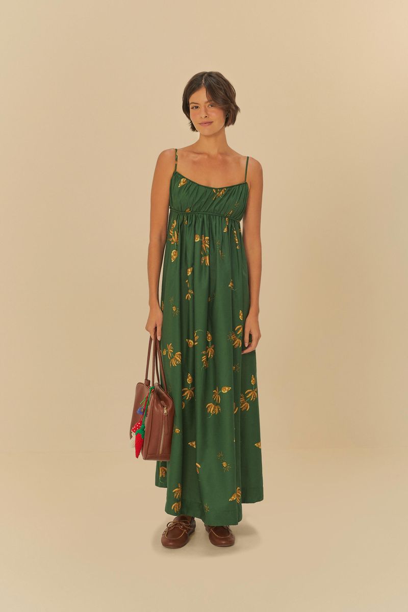 Vestido-largo-verde-con-estampado-de-bananos-amarillos-tirantes-delgados-y-escote-redondeado-modelo-sosteniendo-un-bolso-marron-visto-de-frente.