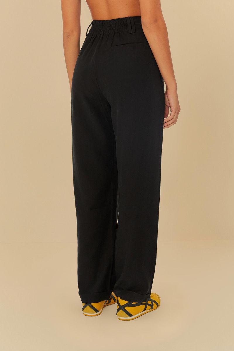 Pantalón negro de sastrería con pinzas, vista posterior, destacando los bolsillos funcionales y el ajuste por elástico.