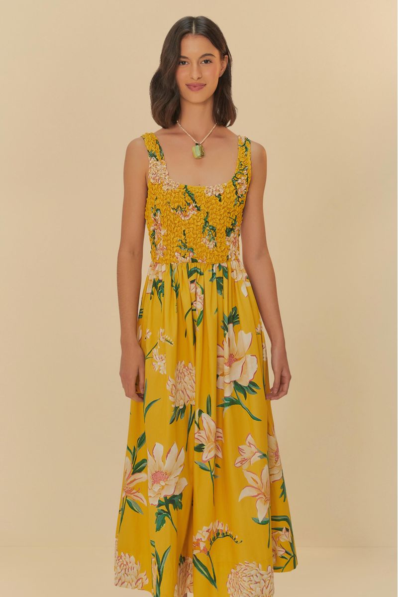 Vestido largo floral amarillo con detalles de flores blancas y verdes, visto desde atrás.