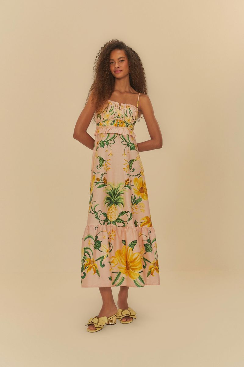 Modelo luciendo un vestido estampado con tirantes delgados y diseño tropical, posando de frente.