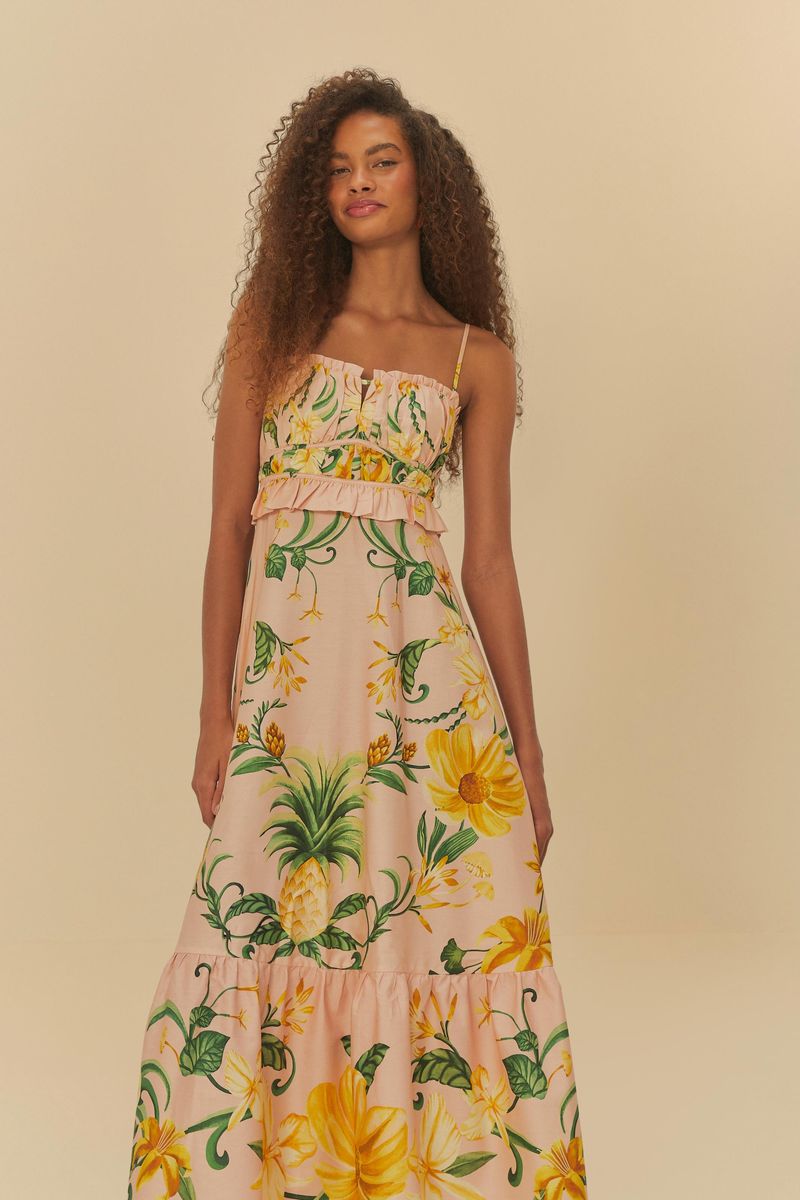 Modelo mostrando la parte trasera del vestido estampado con diseño tropical y tirantes delgados.