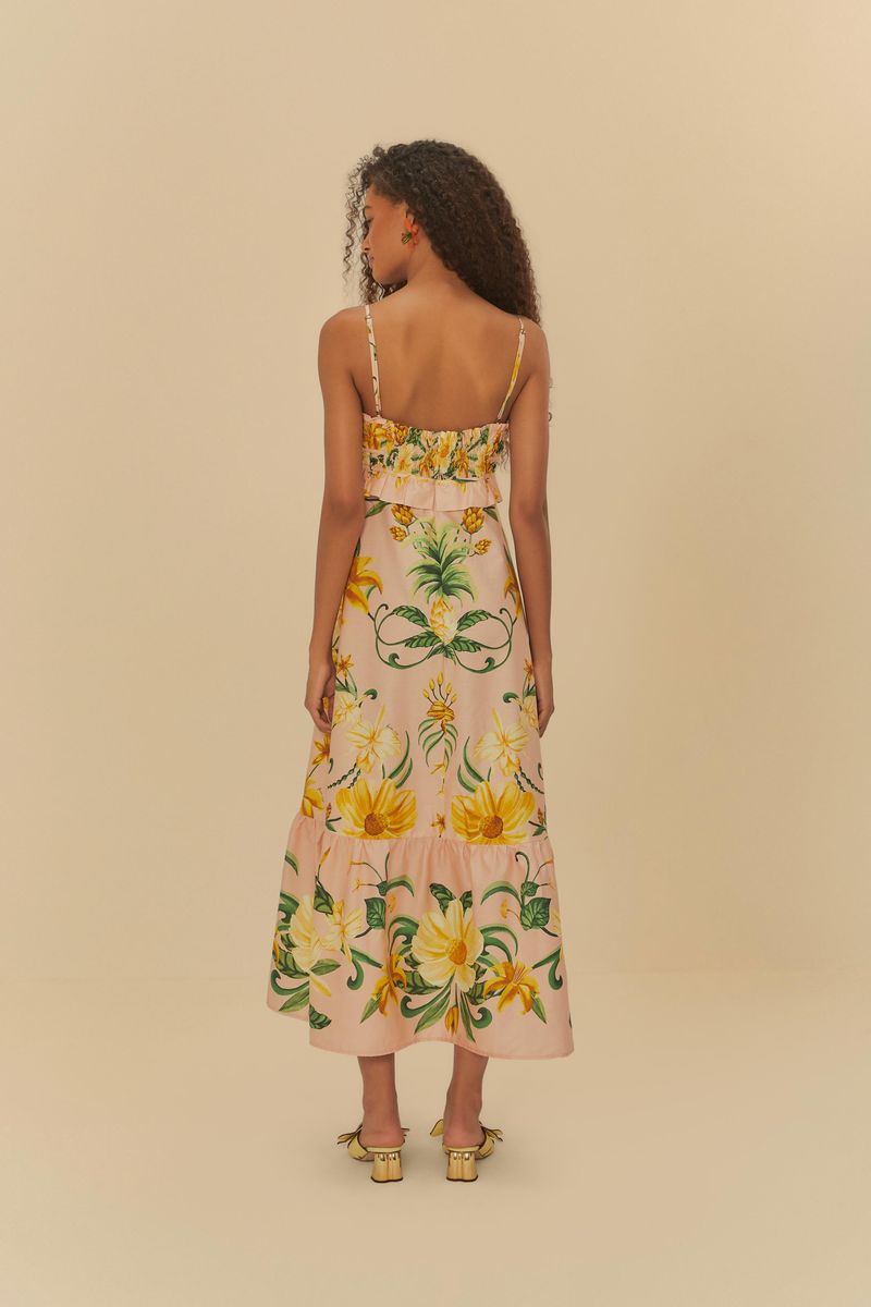 Modelo mostrando el lateral del vestido estampado con diseño tropical y tirantes delgados.