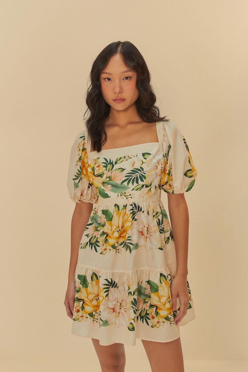 Modelo usando el Vestido Corto Floral Camille con estampado tropical en fondo beige, vista frontal.
