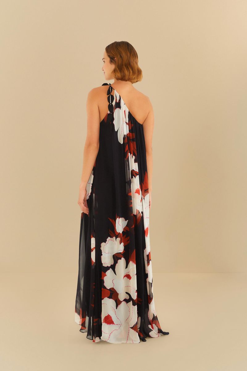 Detalle del vestido largo con estampado floral sobre fondo negro, mostrando el acabado del hombro con lazos.