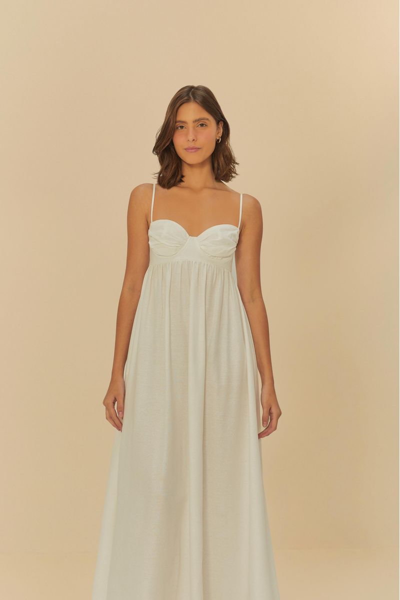 Imagen frontal de una mujer usando un vestido largo fruncido blanco con tirantes delgados.