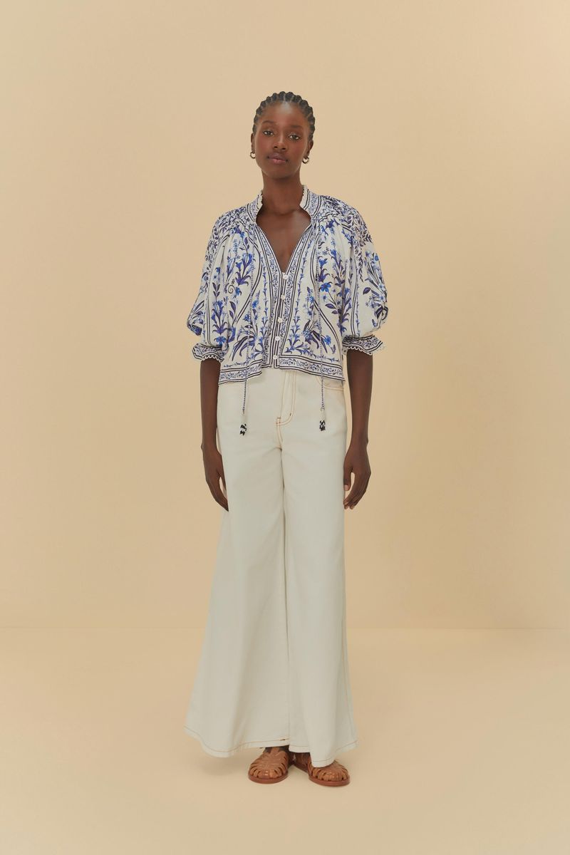 Imagen mostrando la Bata Antonia con estampado floral azul y detalles en encaje, combinada con pantalón blanco.