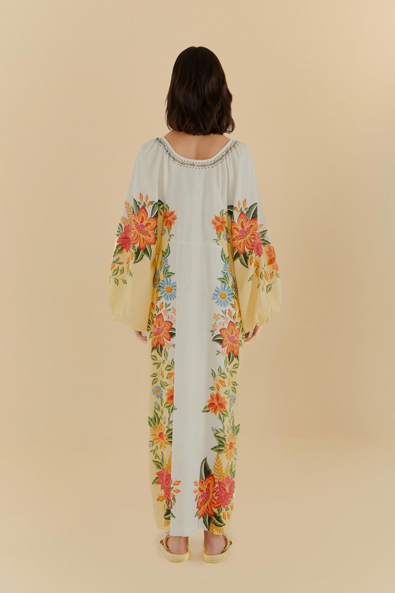 Vista trasera del vestido largo con estampado floral sobre fondo claro, mostrado con mangas amplias y detalles coloridos.