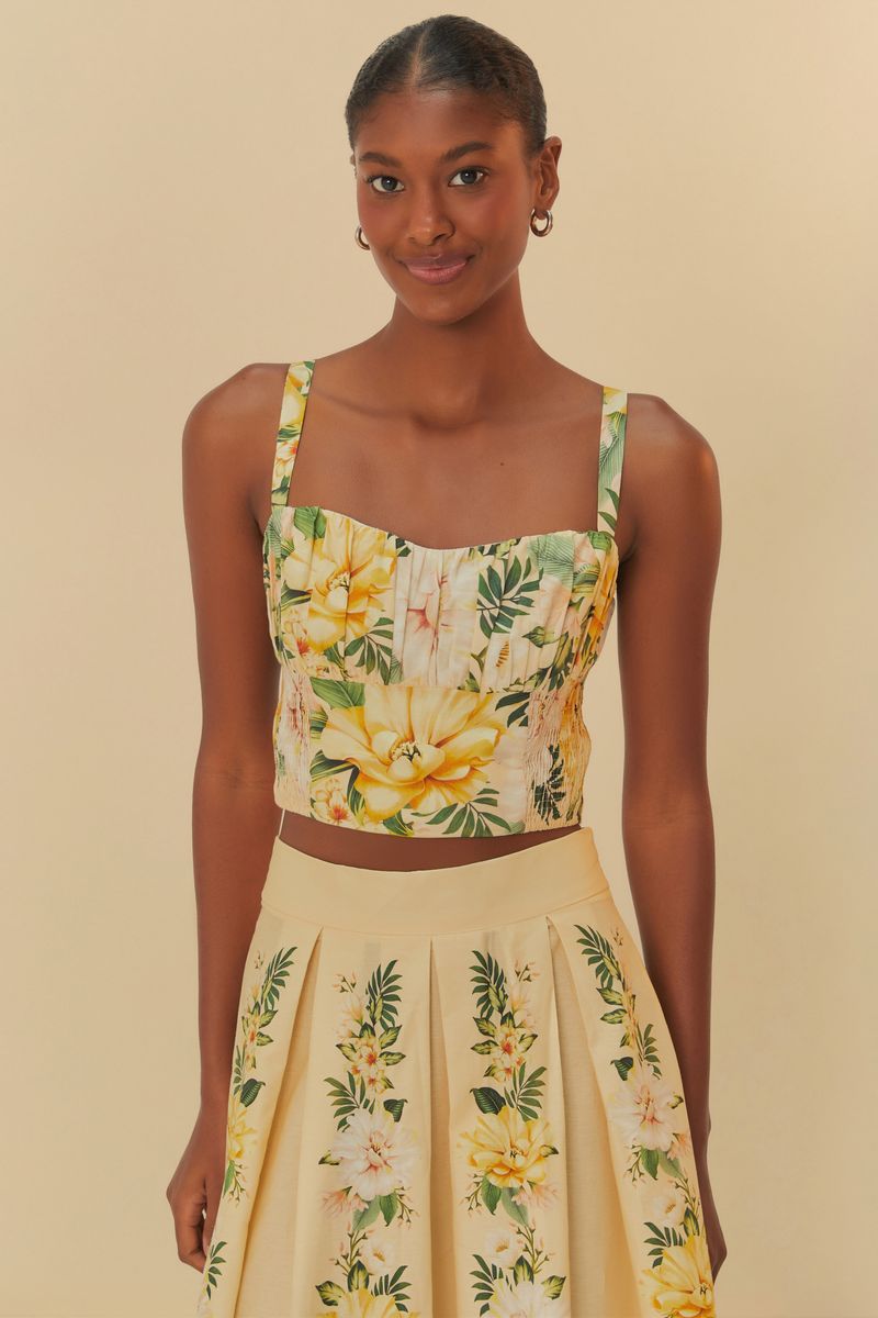 Modelo usando el Top Corset Floral Camille con estampado tropical sobre fondo beige.