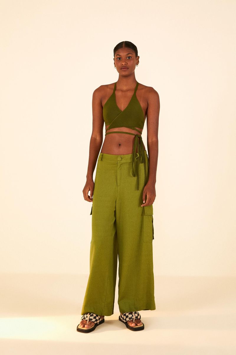 Modelo vistiendo un top de bikini verde con amarre y pantalón cargo.