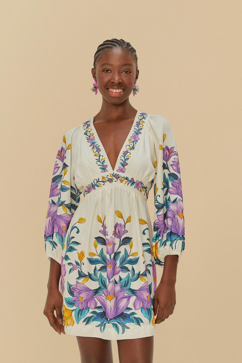 Vestido corto floral con estampado vibrante, escote en V y mangas largas abullonadas, visto de frente.