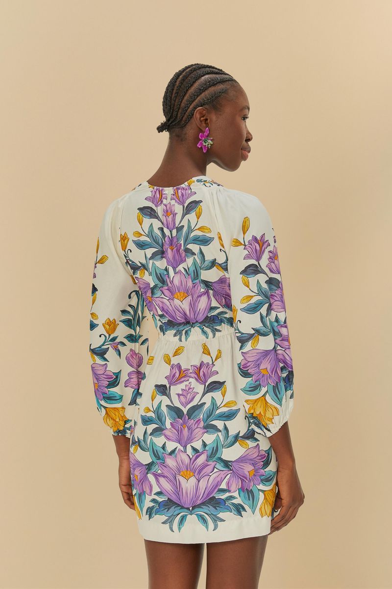 Vista trasera del vestido corto floral con estampado vibrante y mangas largas abullonadas.