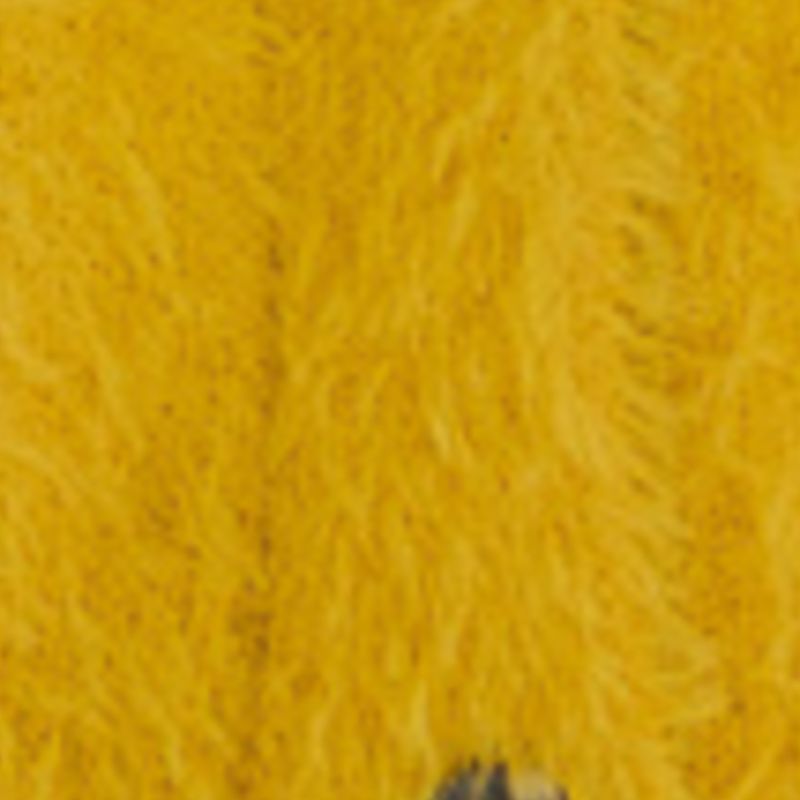 Primer plano de la tela suave del cardigan corto peluche amarillo.